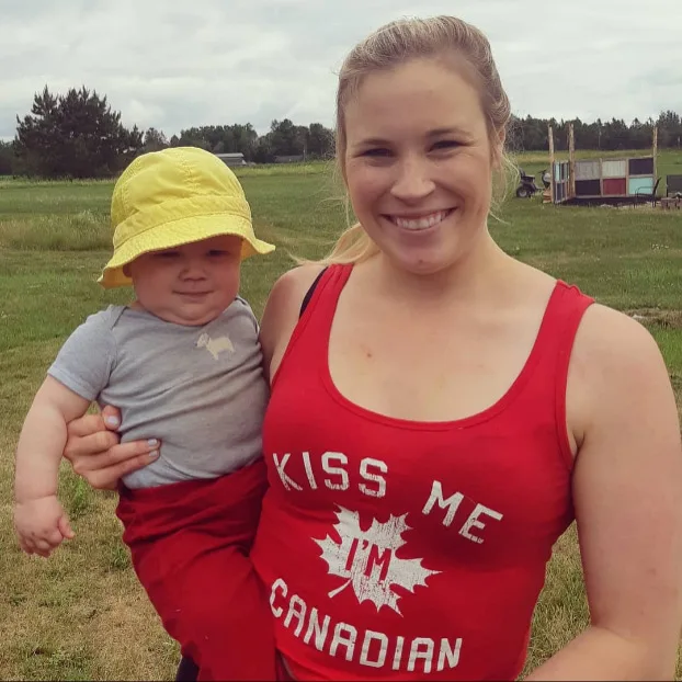 A woman holding her baby in a field.
