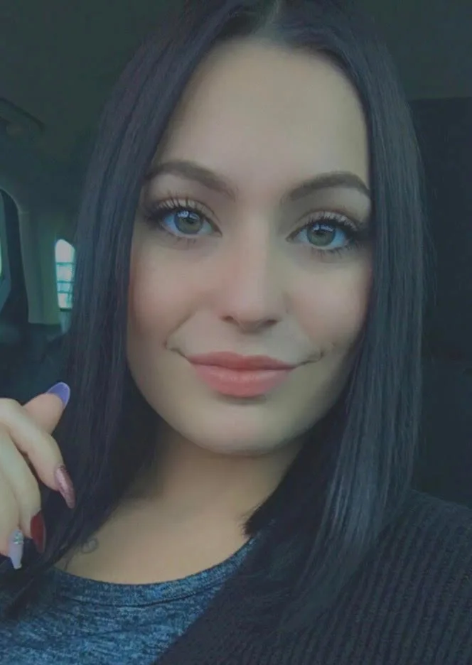 A woman with dark hair and green eyes smiling at the camera.