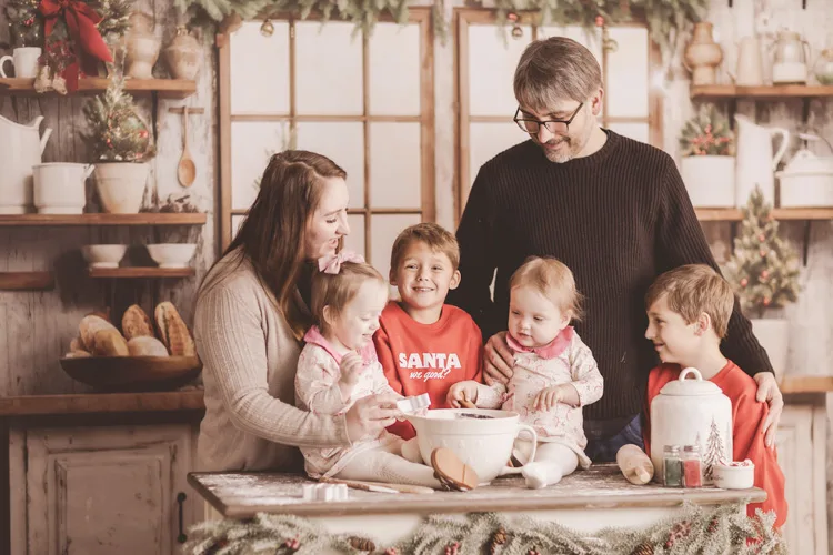A beautiful family of 6 (a mother and father and their 2 sons and 2 daughters) together in their kitchen.